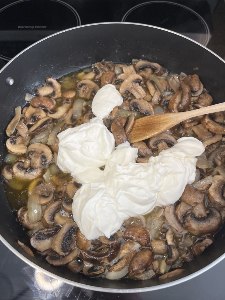 adding sour cream into mushroom sauce